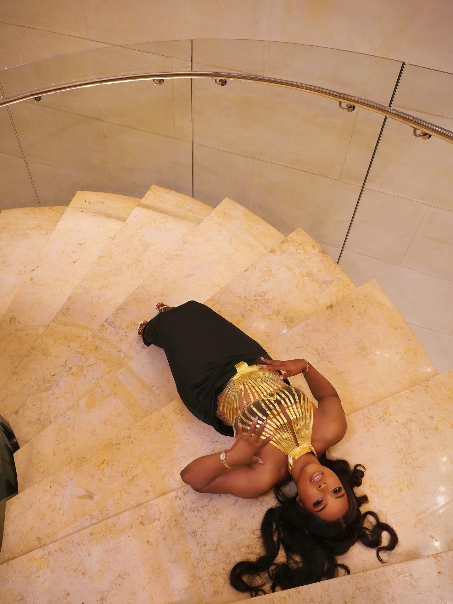 Overhead portrait of the same gold and black outfit arranged along a curved stone staircase.